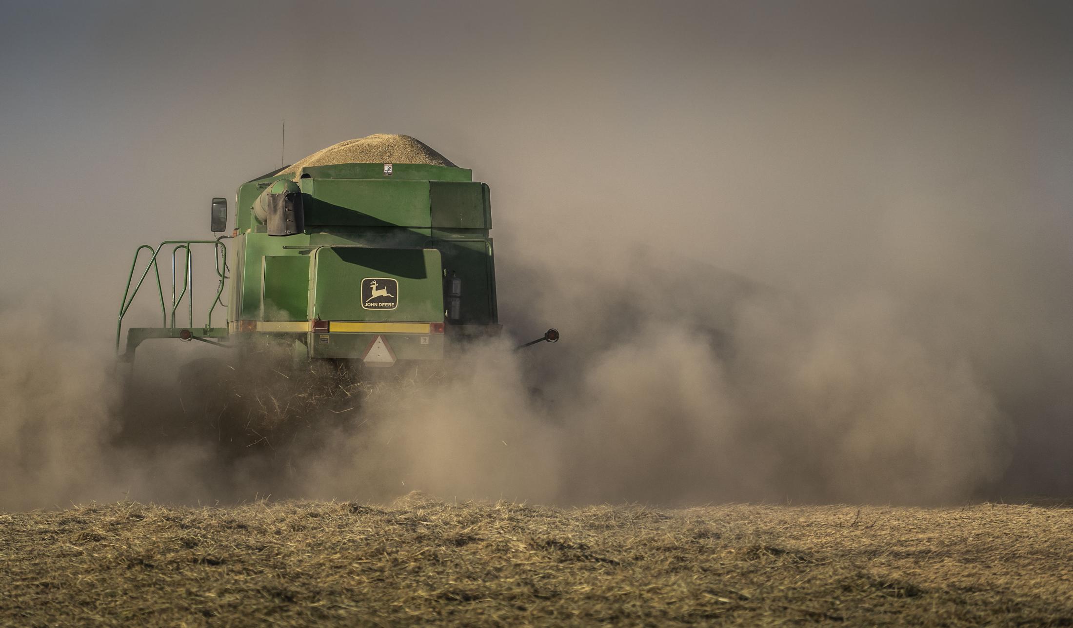 A tractor kicks up dust in a field in California