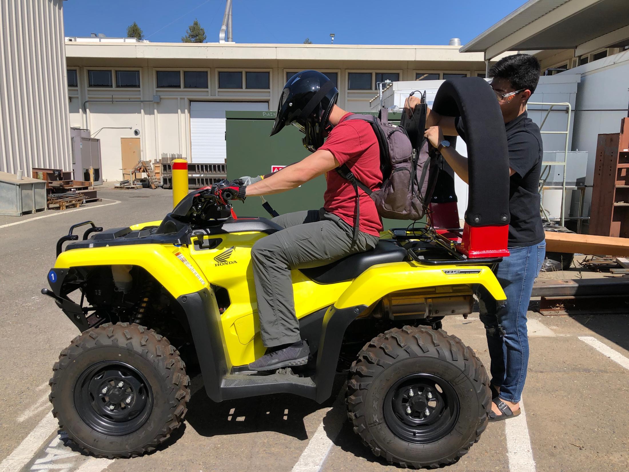 Photograph of yellow ATV with person sitting astride ATV and researcher adding a CPD