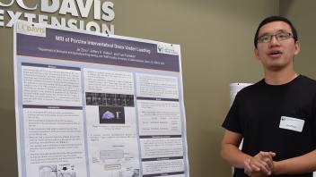 Man stands with hands clasped next to research poster