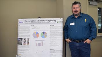 Man stands with hands in his pockets next to his research poster