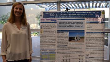 smiling woman stands next to her research poster