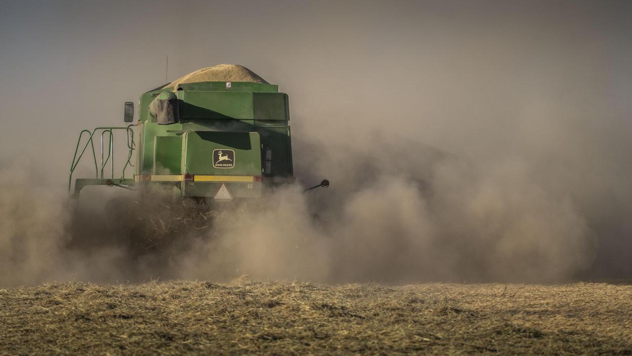 A tractor kicks up dust in a field in California