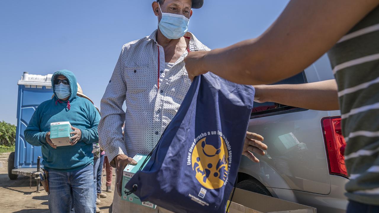 Community organization handing out resources to farmworker in the field