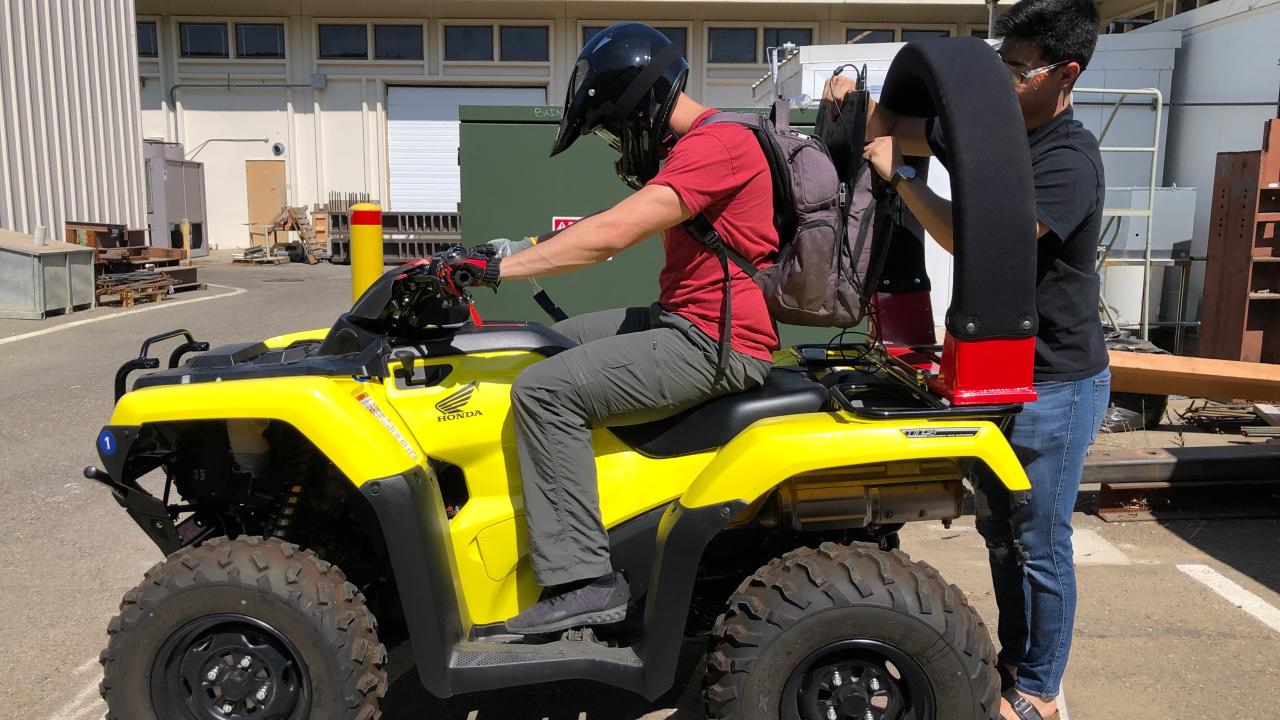 Photograph of yellow ATV with person sitting astride ATV and researcher adding a CPD