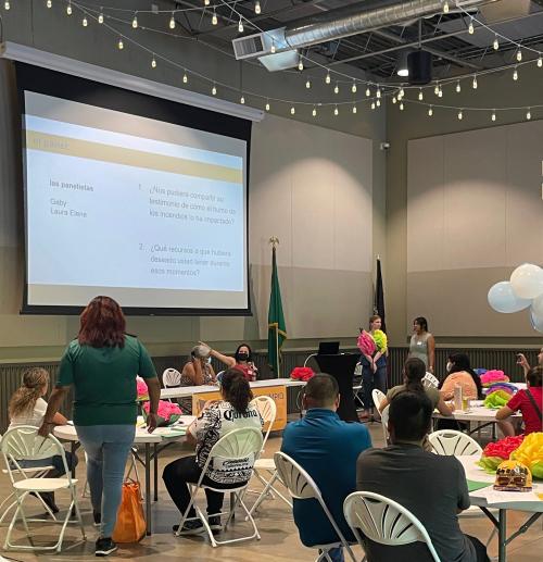 Image shows people sitting in chairs and looking at a presentation