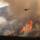 A helicopter drops water on the wildfire in California