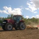 Red tractor stirs up dust in the field